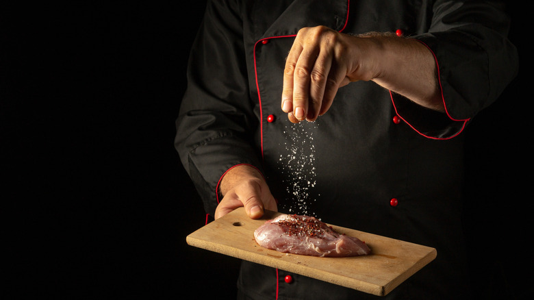 A chef salting chicken