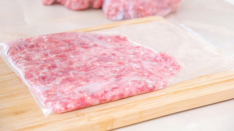 Ground beef divided for storage on a wooden cutting board