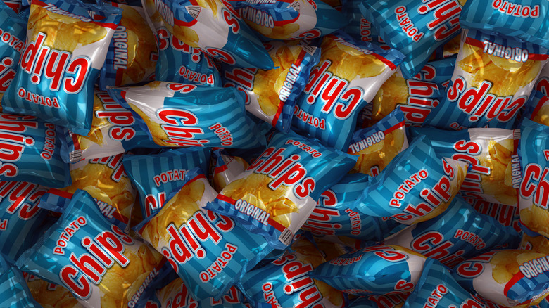 Many snack-size bags of potato chips are piled up.