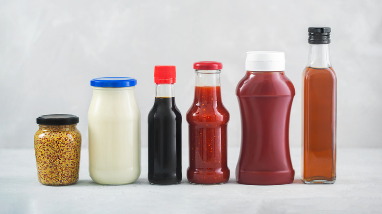 Collection of unlabeled condiments on gray backdrop