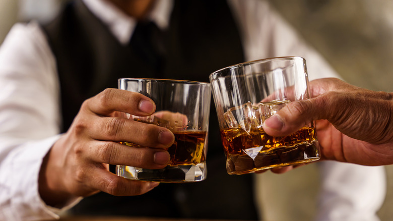 Hands holding glasses of whiskey